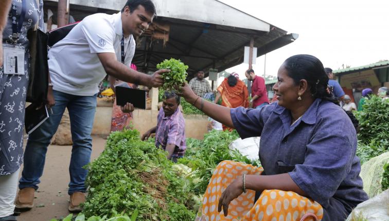 A sitting female hands some herbs to a standing male