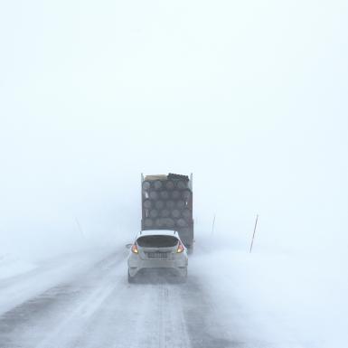 一辆小汽车和一辆卡车在白雪覆盖的路上行驶